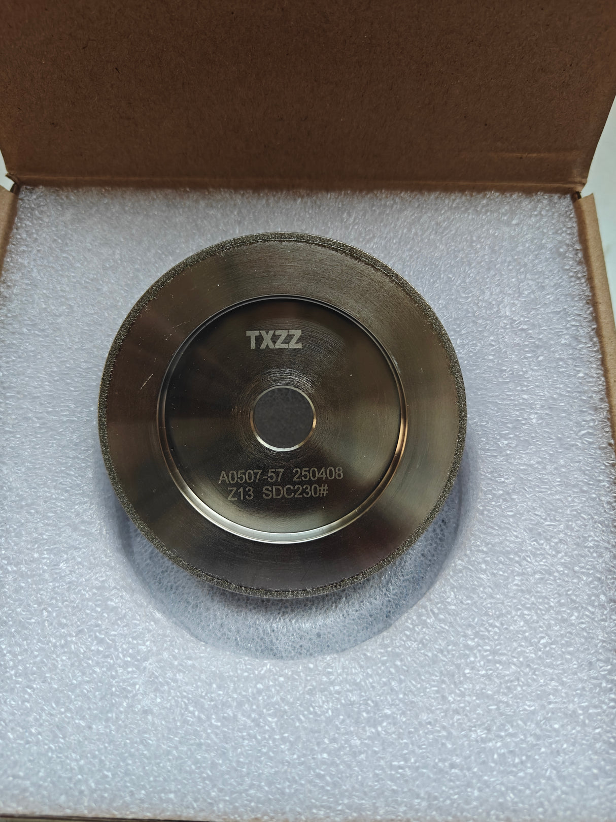 Round metal component with 'TXZZ' branding