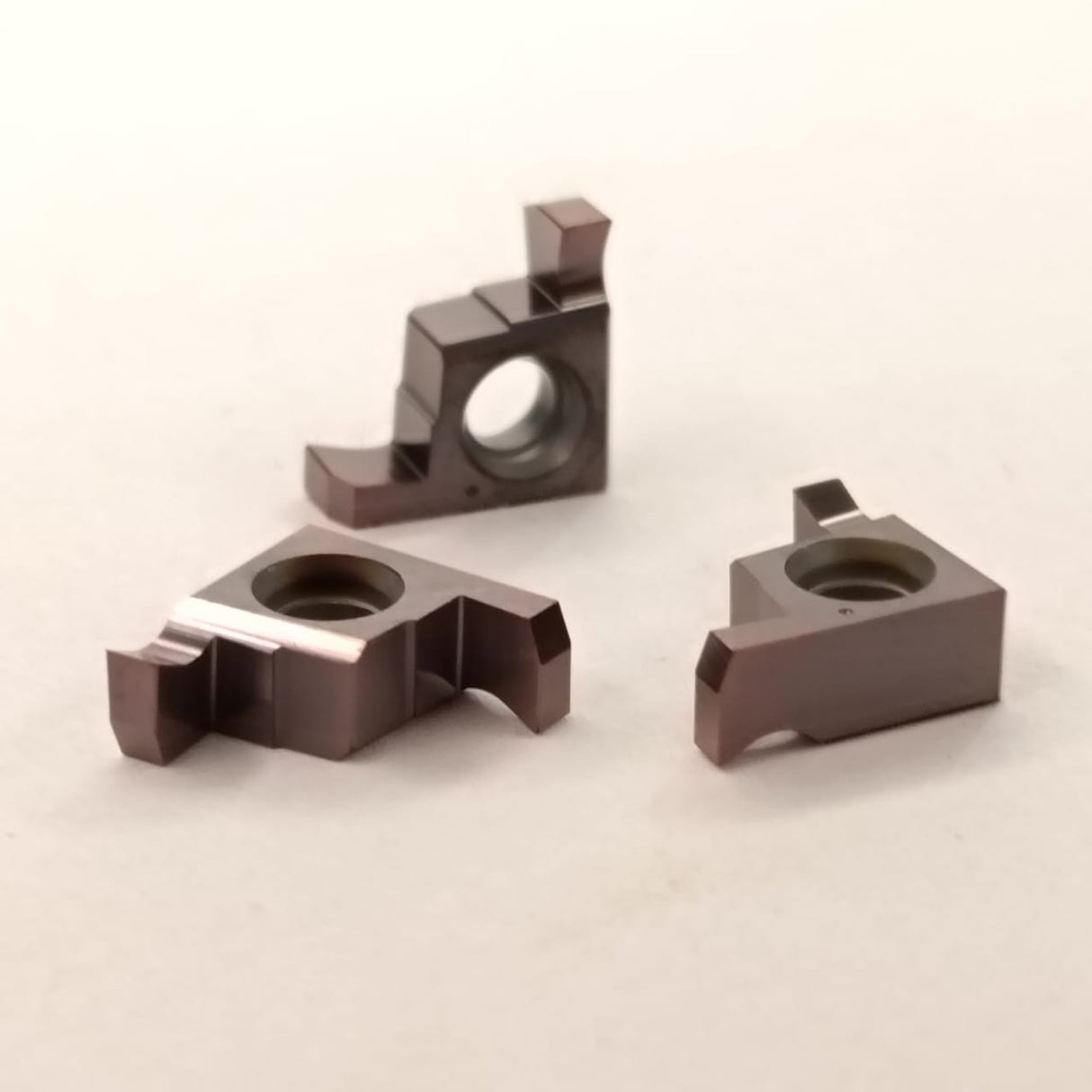 Three metal components on a beige