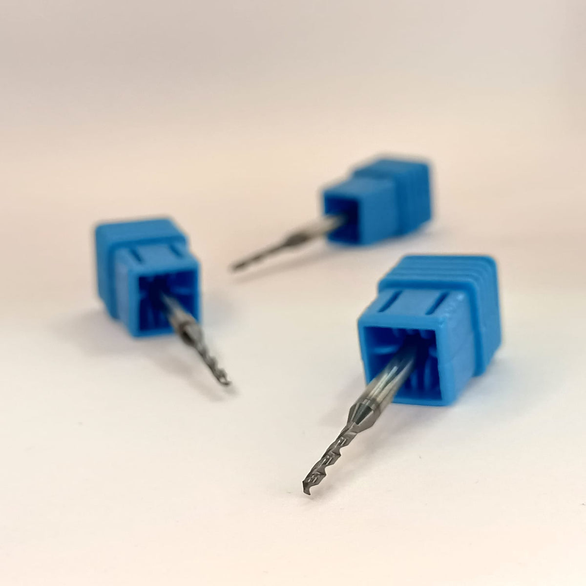 Three blue drill bits on a light