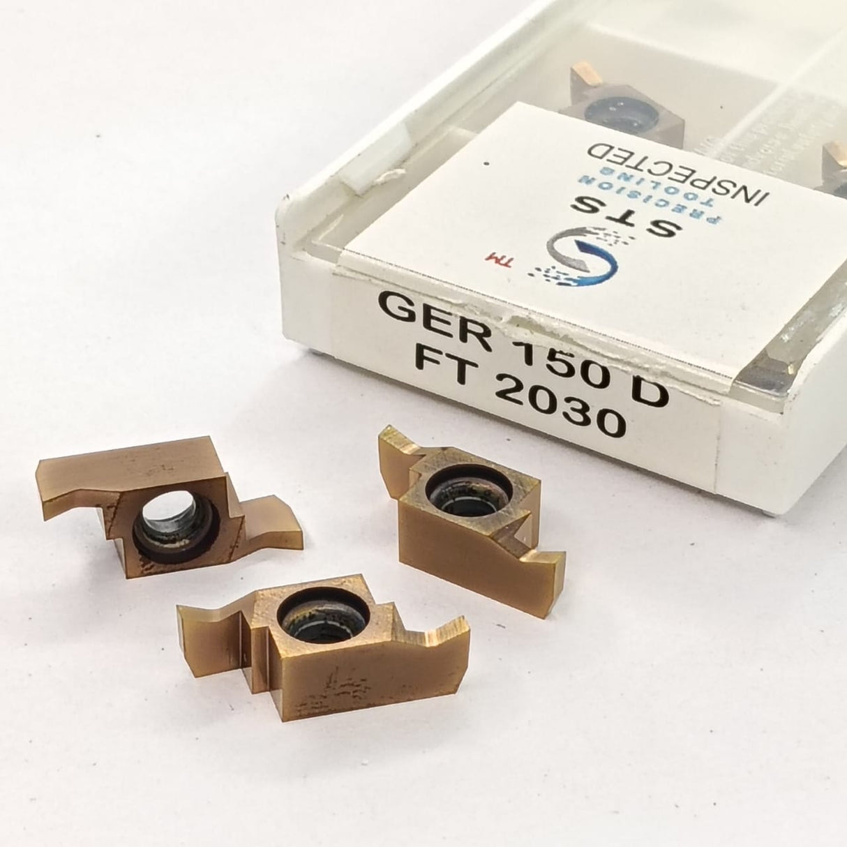 Three metal cutting inserts with a box labeled 'STS'