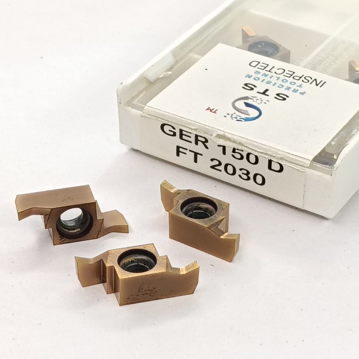 Three metal cutting inserts with a box labeled 'STS'