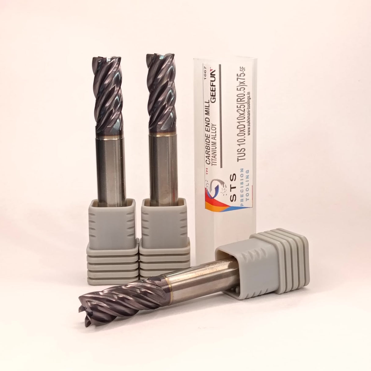 Three cylindrical metal tools with a branded box