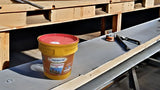 Yellow bucket with red lid on a metal surface